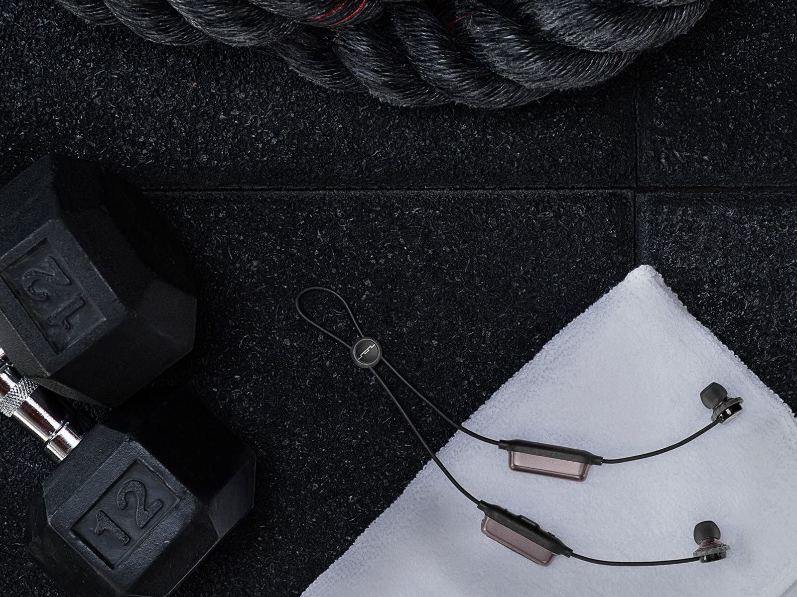 A photo of the headphones lying on the mat in the gym next to the dumbbells