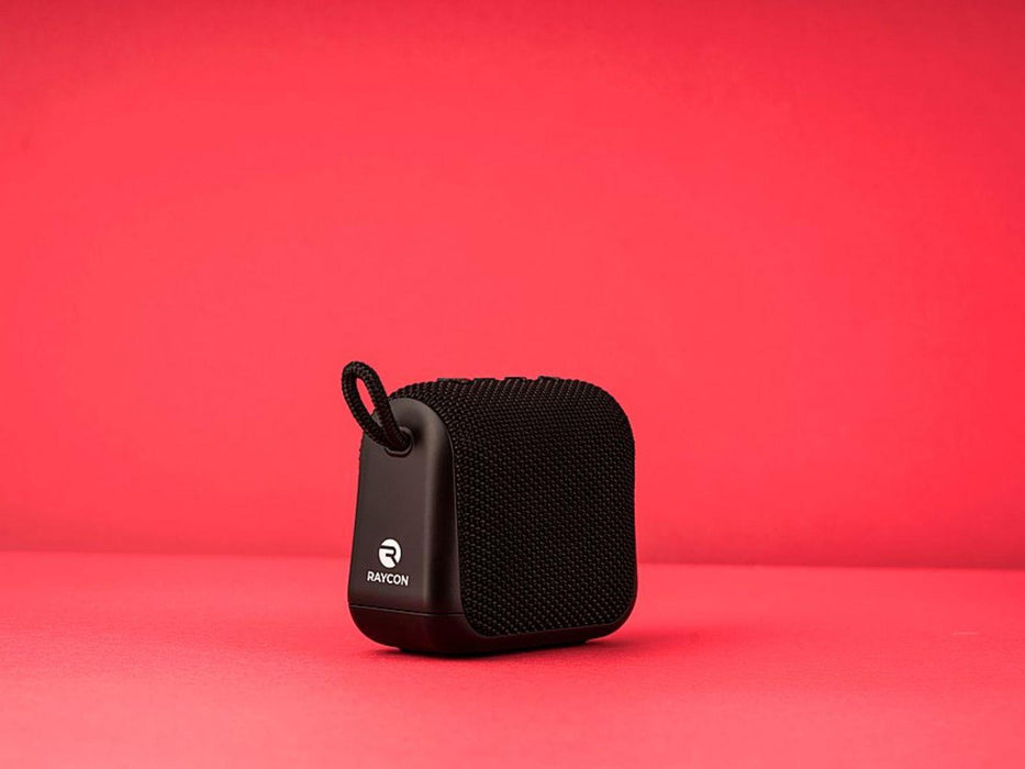 Image shwos the black Raycon Everyday Bluetooth Speaker on a red background